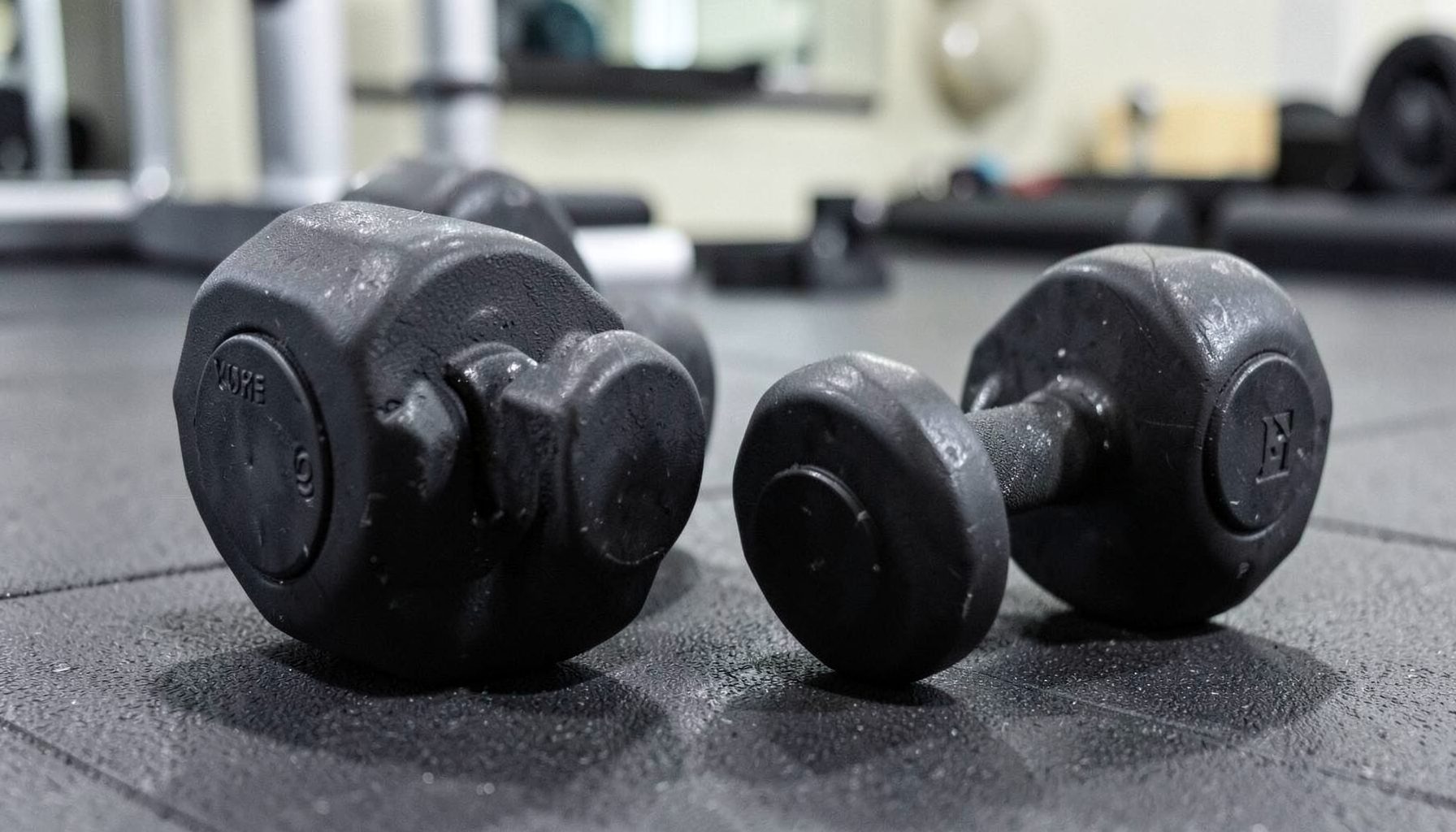 A pair of adjustable dumbbells on a gym mat, clean and simple fitness mood.